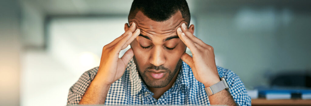 A man massages his temples to help alleviate stress caused by lack of work life balance