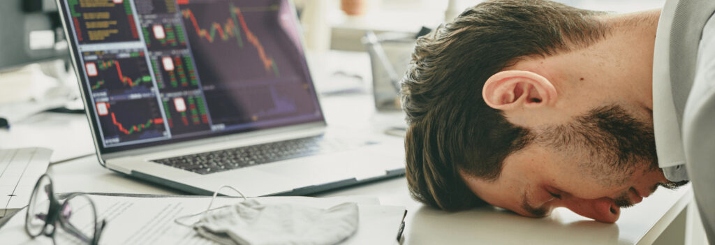 A man, laying his head on a desk, exasperated from failure from autonomy in the workplace