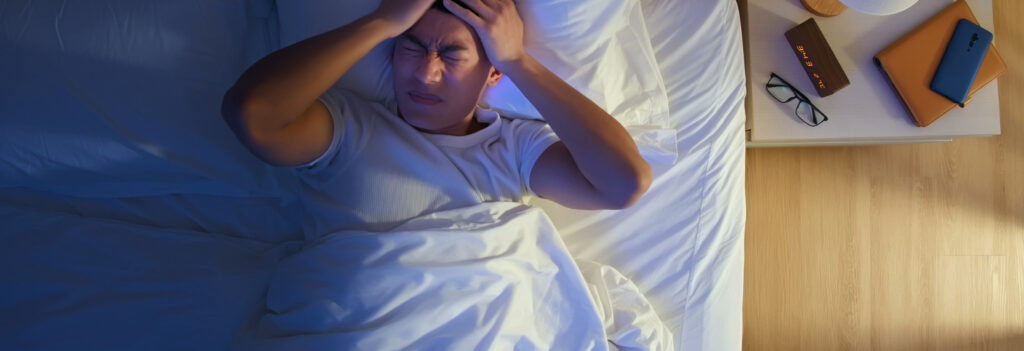 Man struggling with insomnia lays awake in bed, wondering why is sleep important