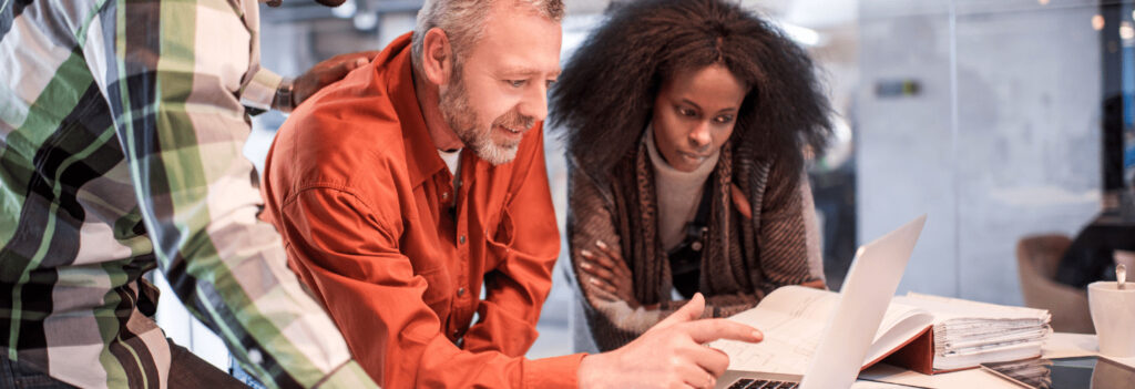 Small team of three people looking at a laptop together