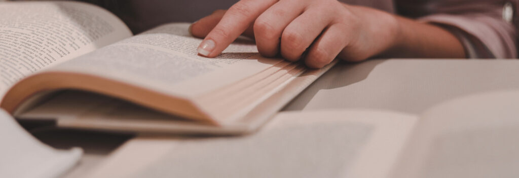 Person pointing at a line in a book while they read