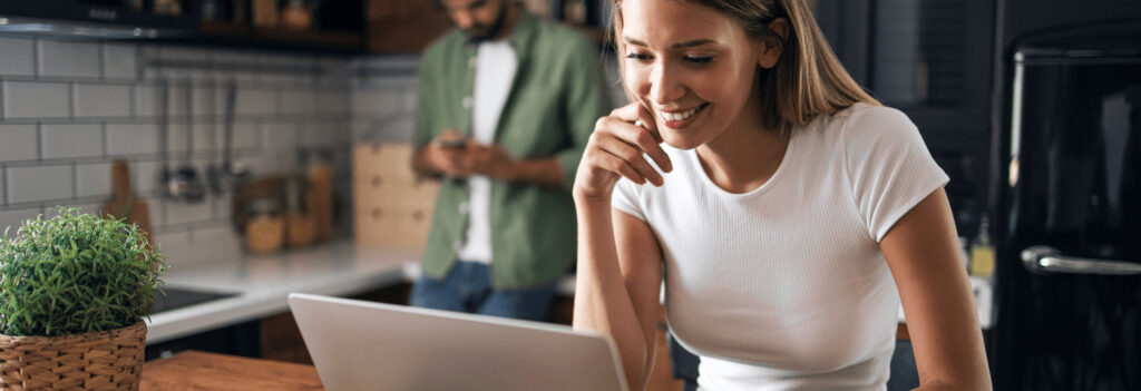 Woman smiling at a computer screen while writing a blog for link building purposes